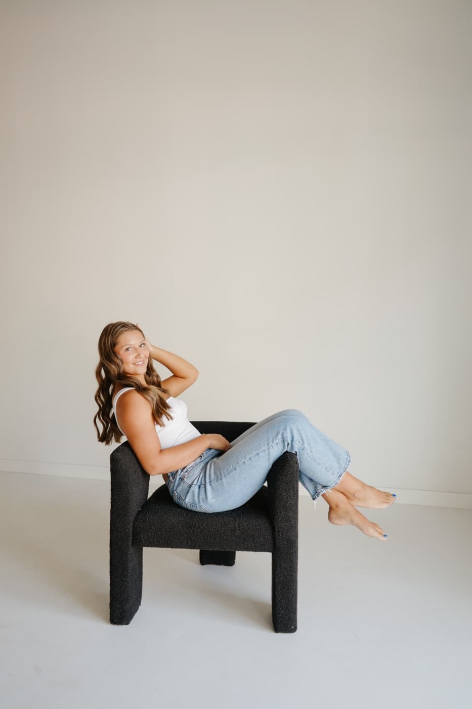 A woman in jeans sitting sideways in the black studio chair